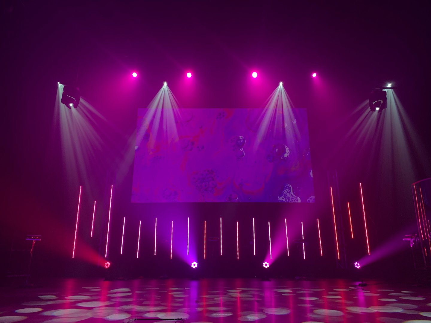 Empty stage with colorful spotlights and a large screen.