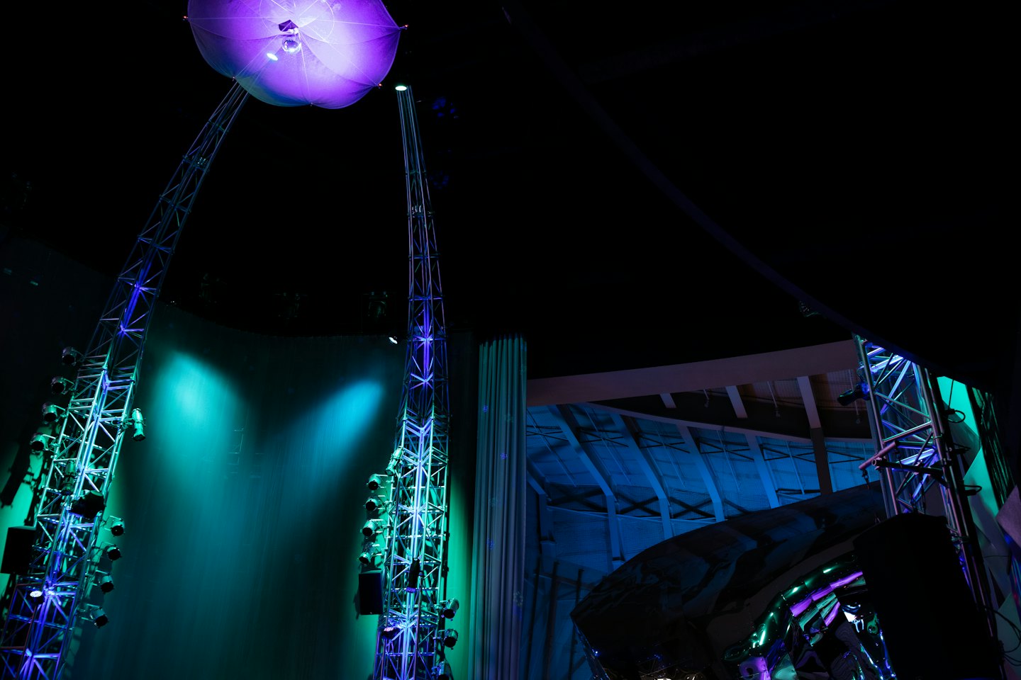 Two illuminated lighting trusses flank a dark stage backdrop.