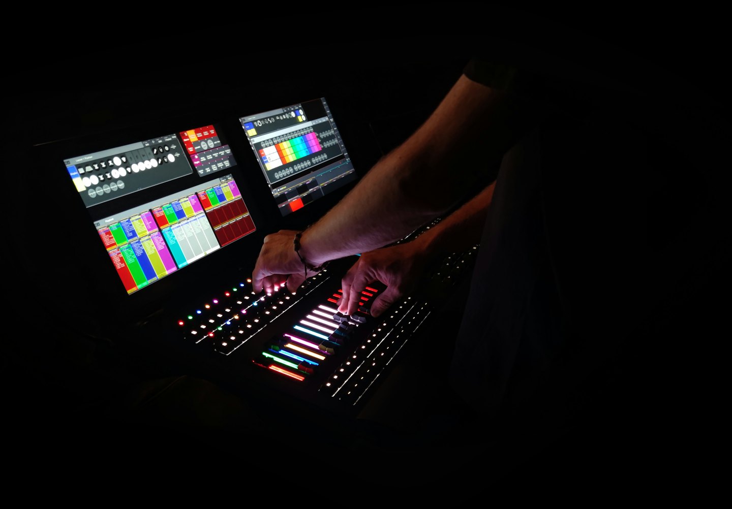 Person operating a digital mixing console with illuminated buttons.