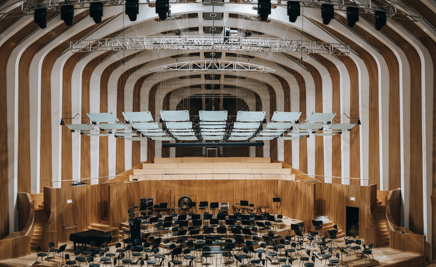 Empty concert hall stage set with musical instruments and wood paneling.