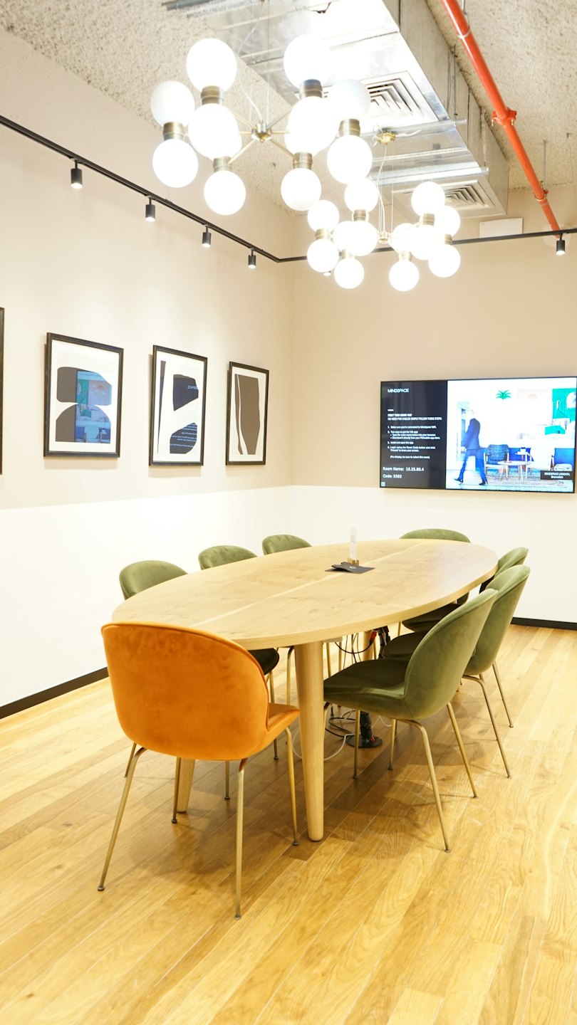Modern conference room with oval table and velvet chairs.