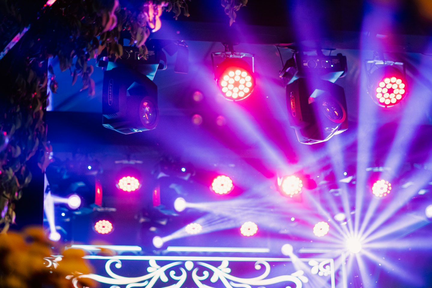 Stage lights project red and purple beams at a concert.